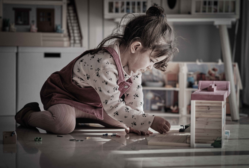 Child kneeling on the floor playing with a dollhouse